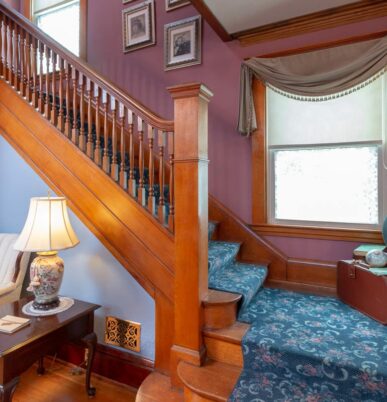 A view of the stairway with blue carpet lining the antique wood floors