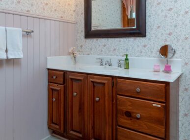 A mirror is lit up by vintage bulb lights above with the sink below in the bathroom