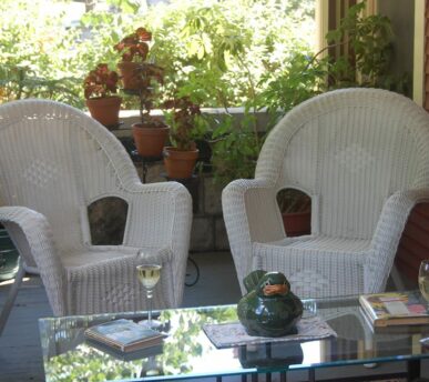 Two chairs next to each other on the porch ready to be sat in and enjoyed by two friends company