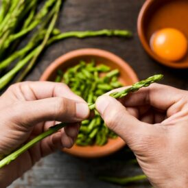 Hands preparing asparagus for a frittata